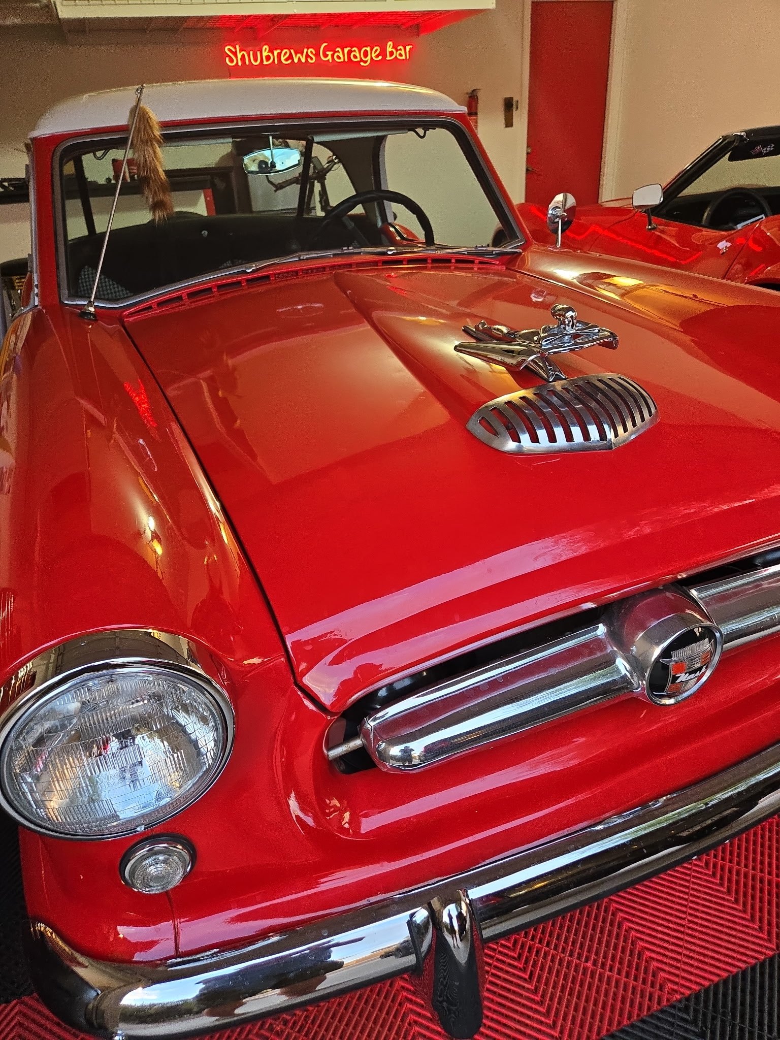 Vintage red convertible with chrome details displayed in ShuBrews Garage Bar showroom in Phoenix.
